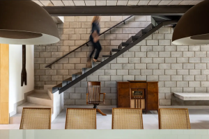 A foto mostra um cômodo de uma casa com uma escada na lateral da parede e uma pessoa subindo.